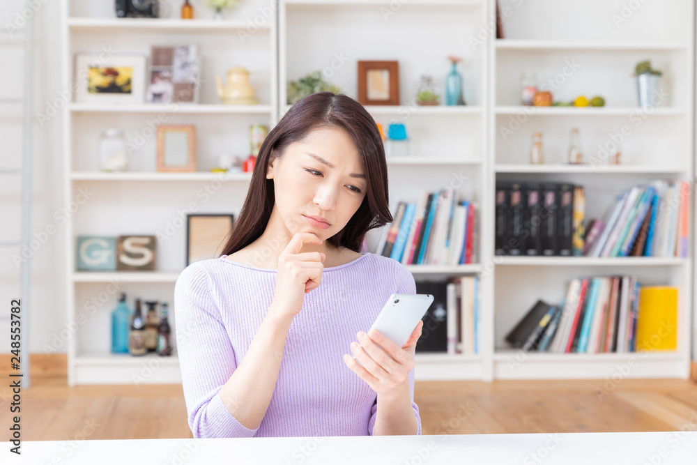 部屋でスマホを見る女性 考える 部屋でスマホを見る女性 考える