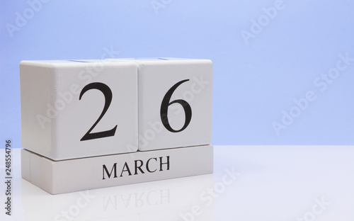 March 26st. Day 26 of month, daily calendar on white table with reflection, with light blue background. Spring time, empty space for text photo