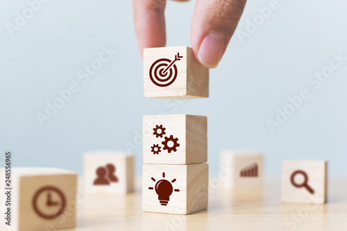 Concept of business strategy and action plan. Businessman hand putting wood cube block on top with icon photo