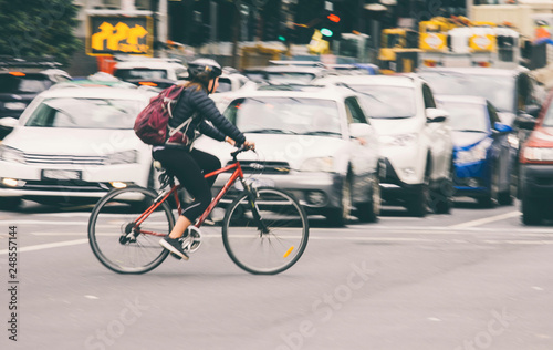Woman cyclist riding bicycle on city street 
