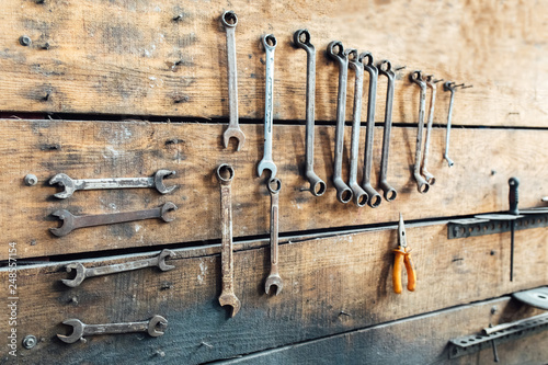 Workshop scene. Old tools hanging on wall in workshop. Vintage retro garage style. Old wrenches hanging wall in old garage.