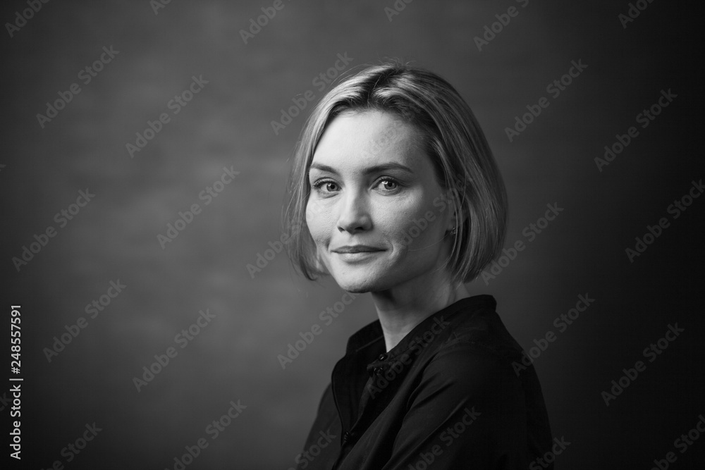 Fototapeta premium Black and white portrait of a beautiful smiling woman on a dark background