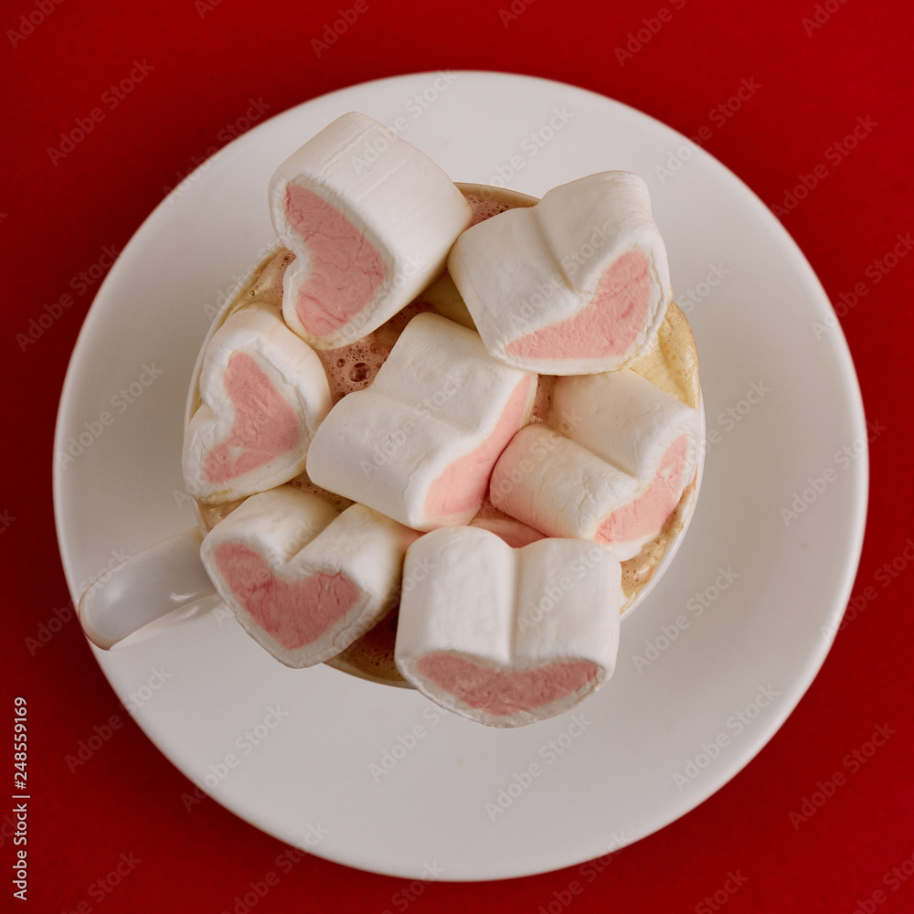 Pink sweet marshmallow hearts in a cup on the red background. Valentine's day background Pink sweet marshmallow hearts in a cup on the red background. Valentine's day background