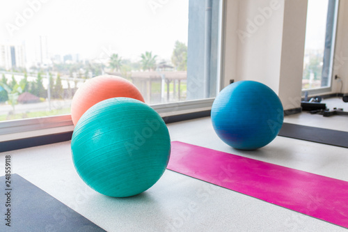 Colorful pilates balls and exercise sports equipments indoor concept image background. Gym interior.