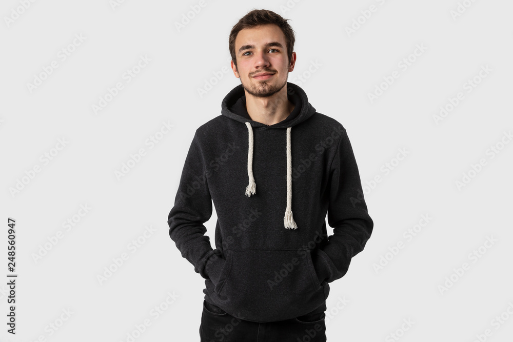 Portrait of satisfied caucasian young man with hands in his hoodie. Isolated on white background. Portrait of satisfied caucasian young man with hands in his hoodie. Isolated on white background.