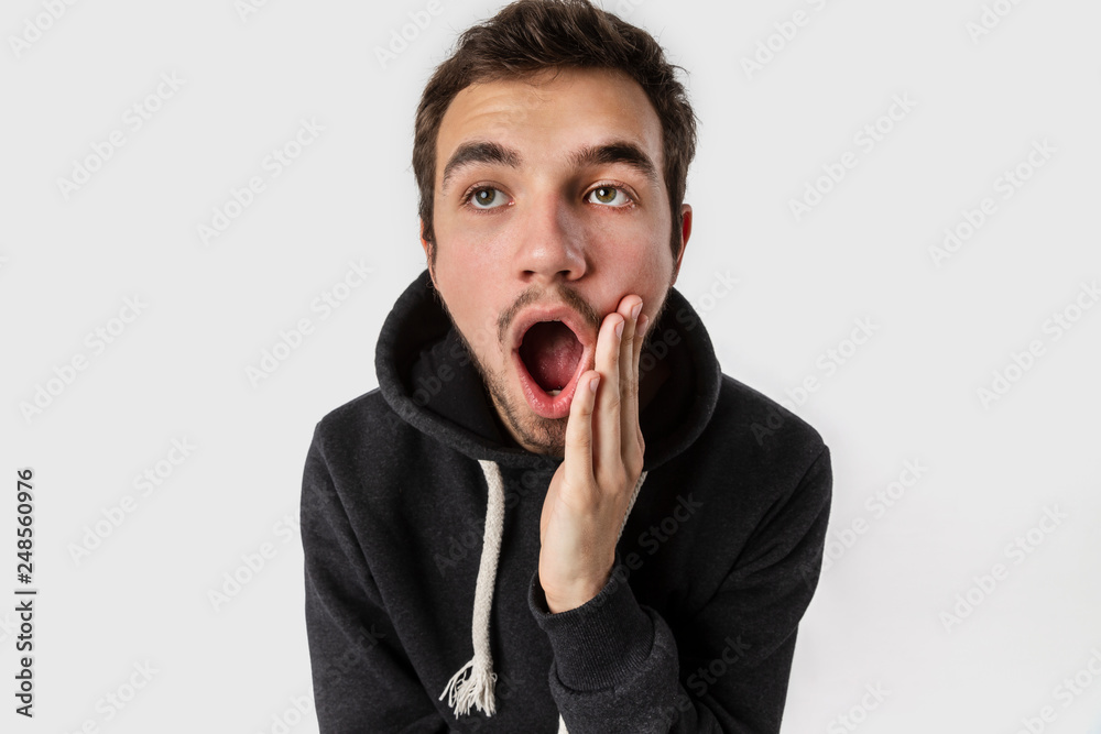 Surprised caucasian young man with arm on his cheek. Isolated on white background. Surprise concept. Surprised caucasian young man with arm on his cheek. Isolated on white background. Surprise concept.