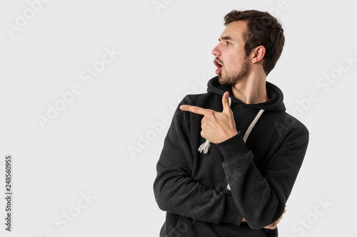 Amazed caucasian young man pointing at blank space. Isolated on white background. Advertisement concept.