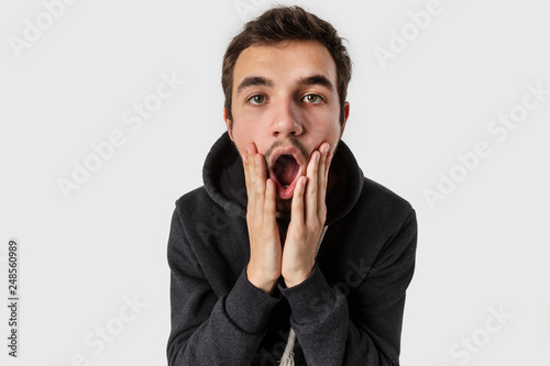 Surprised caucasian young man with arms on his cheeks. Isolated on white background. Surprise concept. © Maksym