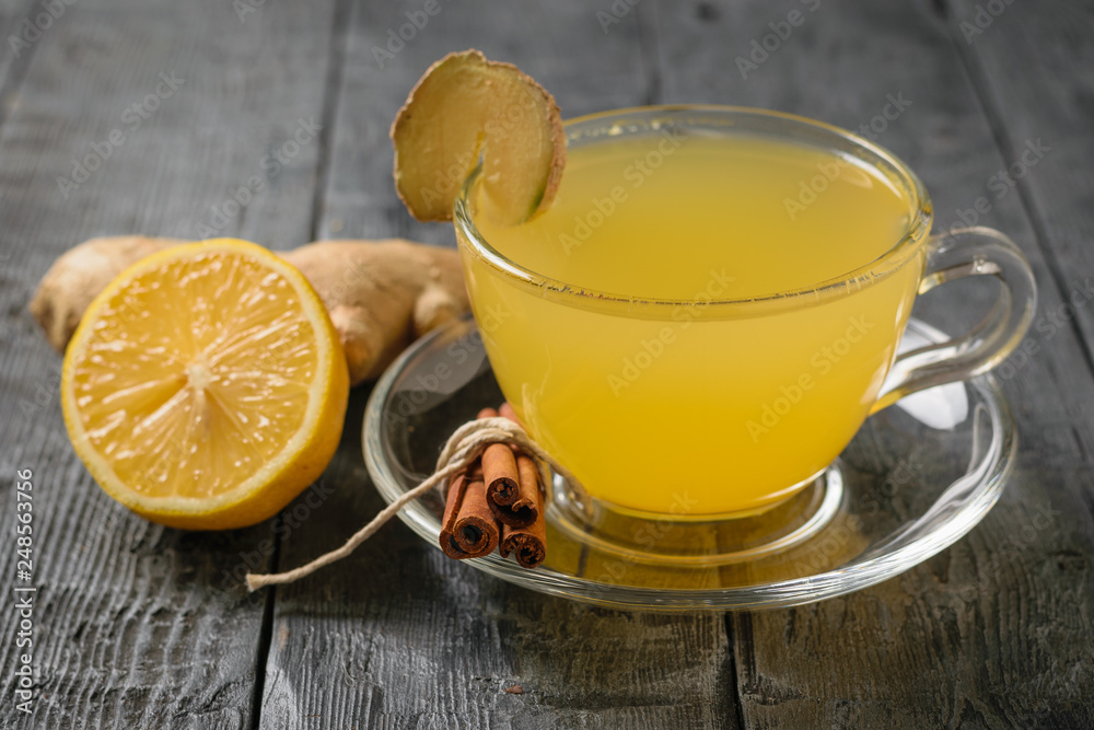 Glass bowl with saucer filled with fresh drink and ginger root, lemon, orange, honey and cinnamon.