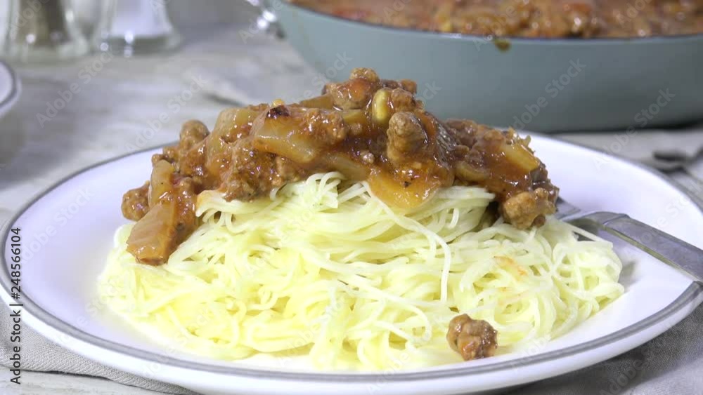 Spooning spaghetti sauce with meat over hot steaming spaghetti noodles Spooning spaghetti sauce with meat over hot steaming spaghetti noodles