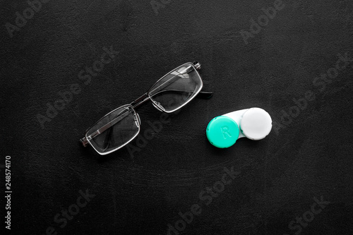 Eyes care. Glasses with transparent lenses and contact lenses on black background top view space for text