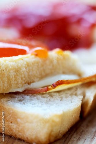 Ham cheese sandwich and tomato ketchup and chili sauce on wood tray and space for write wording, easy delicious food served with coffee or tea in coffee shop or office, popular food for office worker