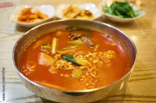 A bowl of kimchi ramen with side dishes in the background