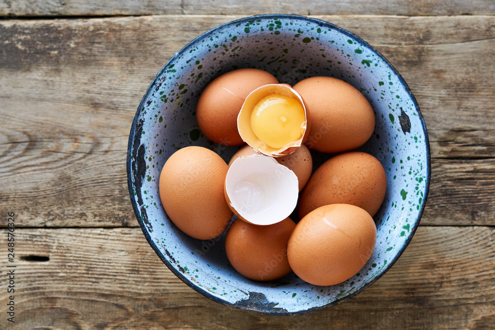 Raw chicken eggs in a metal bowl on a wooden background Raw chicken eggs in a metal bowl on a wooden background