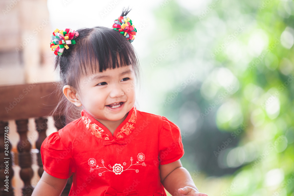 Happy cute asian little child girl in chinese tradition dress smiling and wishing you a happy in Chinese New Year Happy cute asian little child girl in chinese tradition dress smiling and wishing you a happy in Chinese New Year