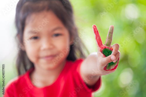Cute asian little child girl with painted hands showing  fingers number two