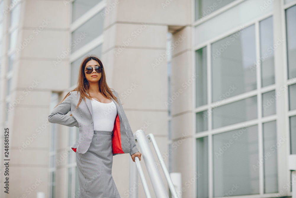 Beautiful businesswoman in a city. Businesswoman in a elegant dress. Lady in a city. Pretty girl with sunglasses