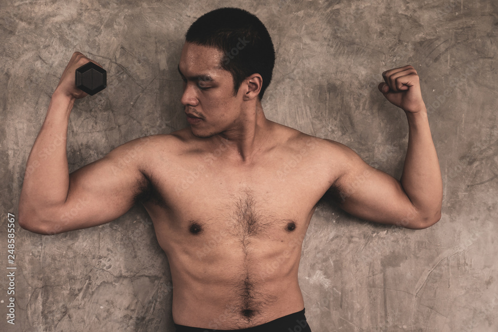 Portrait of Attractive young man with dumbbell on grunge background.