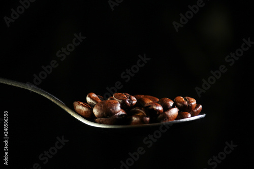 A spoon with coffee beans at dark background