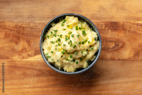 Pomme puree, an overhead photo of a bowl of mashed potatoes with herbs, shot from the top on a rustic background with a place for text photo