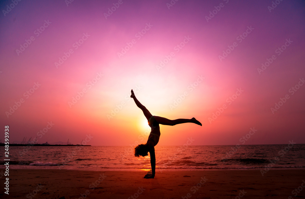 Beautiful young woman practic yoga at the beach. Early morning exercise. Sunrise