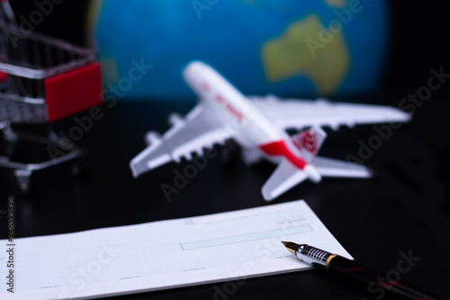 Travel concept. Cheque book,shopping cart,airplane and globe model with dark background. Business trip and travel for shopping online and paycheck concept.