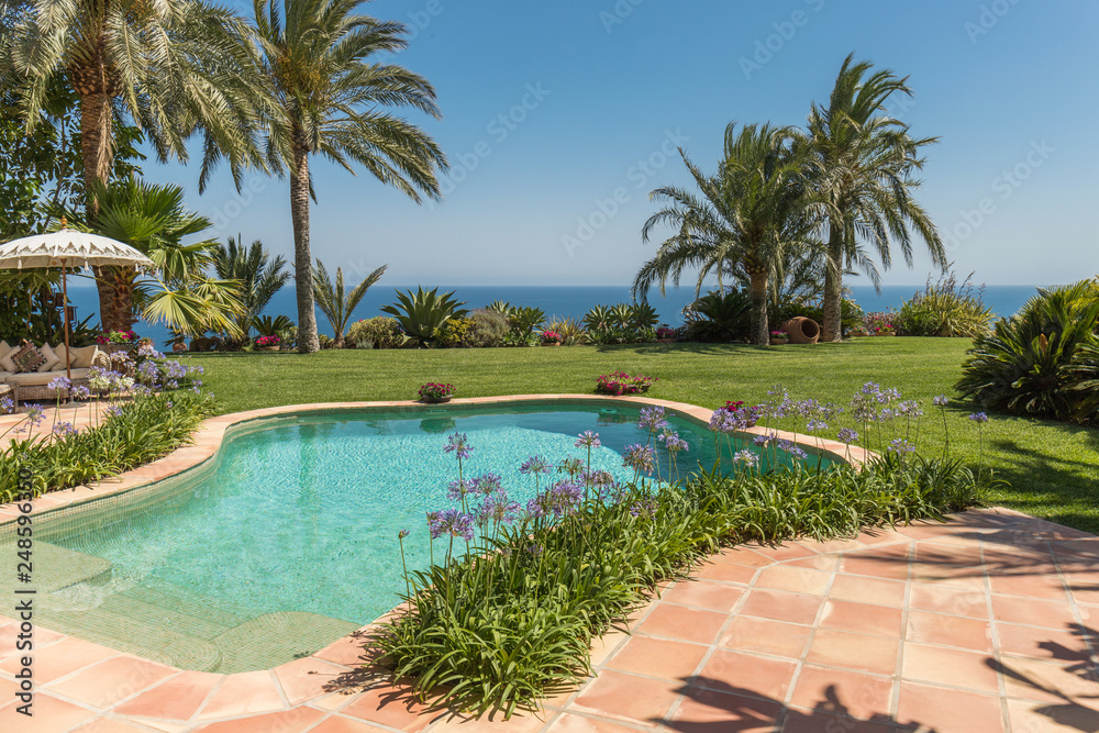 Fototapeta premium Beautiful blue swimming pool in resort or home on summer paradise with coconut trees or palm trees in the background. Holiday or holiday with sophistication and decoration with glamorous style
