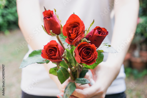 Woman holding red roses in the garden.