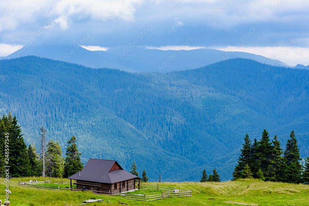 Beautiful mountains landscape with green meadow and modern wooden house