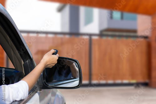 Woman in car, hand holding and using remote control to open the auto gate. Security system concept. 