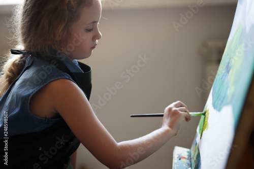 Preschool girl painting in art class. Close up photo brush in hand