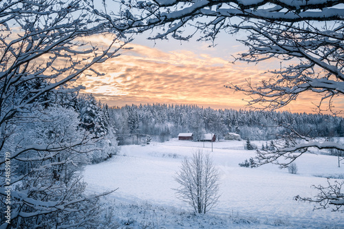 Scenic winter landscapw with farm house and sunset at evening light in Finland