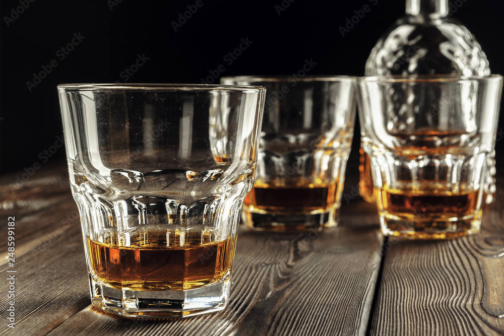 Whiskey glass and bottle on the old wooden table Whiskey glass and bottle on the old wooden table