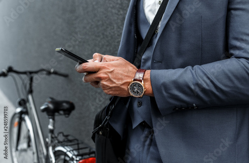 Close up of businessman hands using smartphone on the street.
