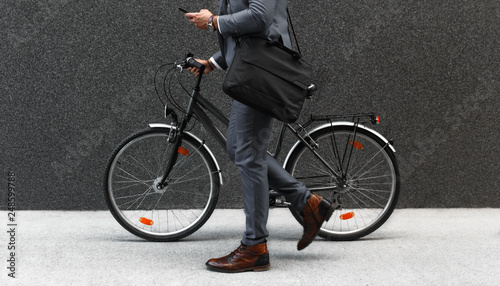 Businessman going to work with his bicycle and looking at phone.	 photo