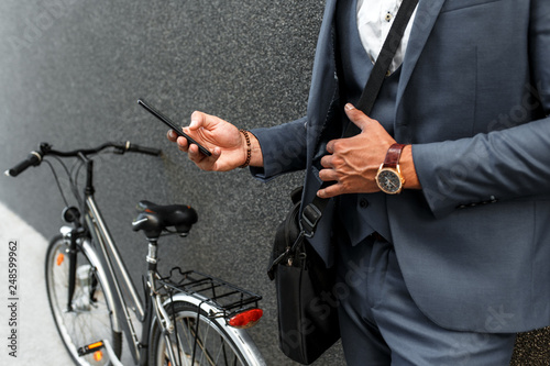 Close up of businessman hands using smartphone on the street.
