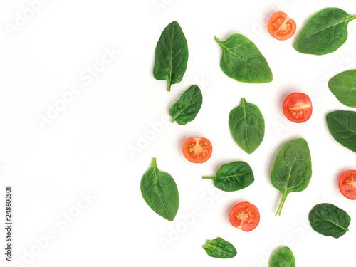 spinach and slices of baby tomatoes on a white background, top view with copy space, mock up