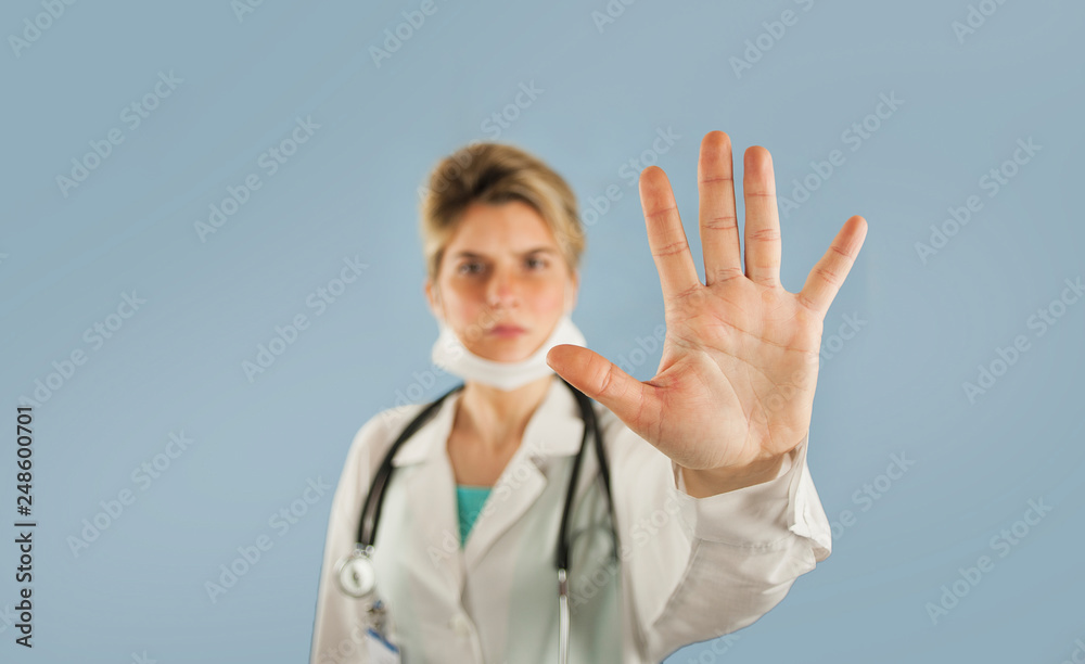 girl doctor shows with hand palm stop sign on a blue isolated background.Concept medicine and health girl doctor shows with hand palm stop sign on a blue isolated background.Concept medicine and health