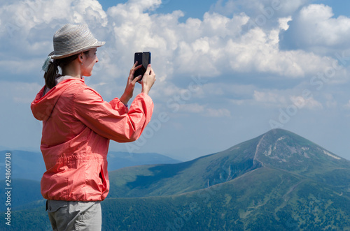 Young woman take photo of the scenic mountain landscape.