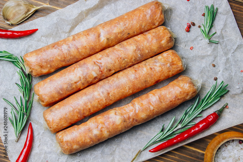 Raw Tyrolean sausages with rosemary over wooden background