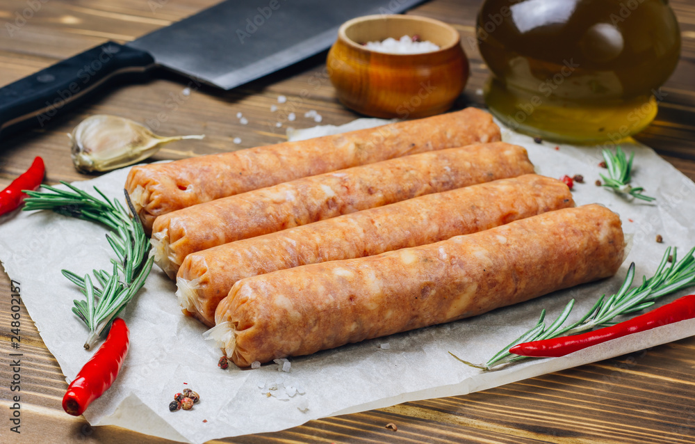Raw Tyrolean sausages with rosemary over wooden background Raw Tyrolean sausages with rosemary over wooden background