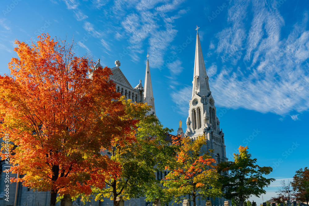 Fototapeta premium Exterior view of the Basilica of Sainte-Anne-de-Beaupre church with red maple tree