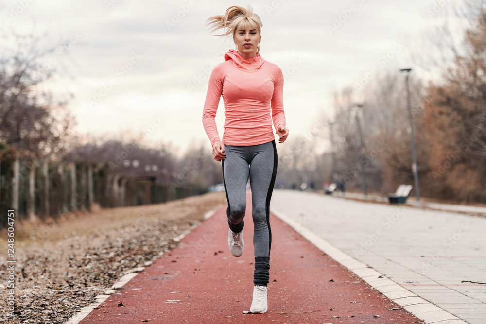 Gorgeous dedicated blonde Caucasian woman in sportswear and with ponytail  running on the racetrack. Stock Photo | Adobe Stock