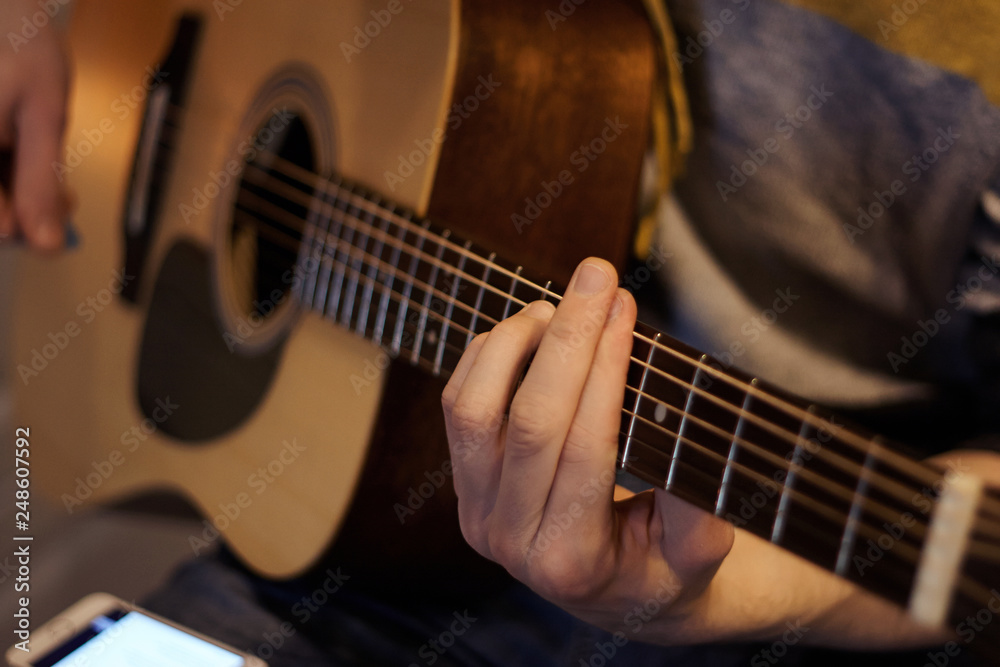 The singer plays the song on an acoustic guitar, holding on his knee smartphone, which is written lyrics The singer plays the song on an acoustic guitar, holding on his knee smartphone, which is written lyrics