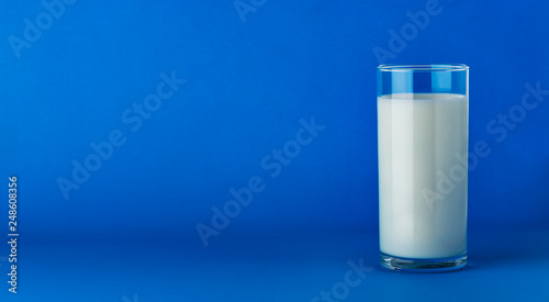Glass of milk isolated on blue background with copy space