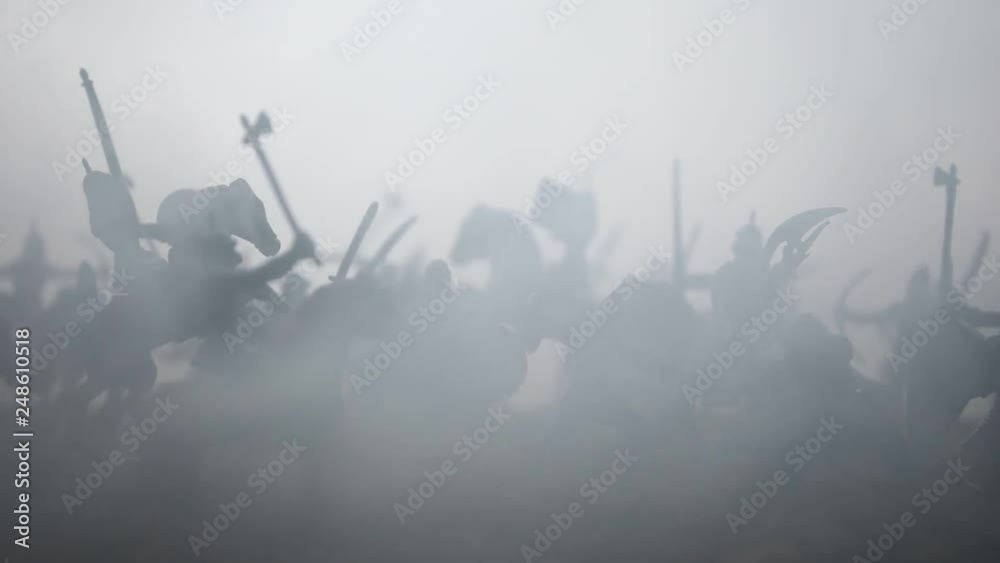Medieval battle scene with cavalry and infantry. Silhouettes of figures as separate objects, fight between warriors on sunset foggy background. Artwork decoration. Selective focus