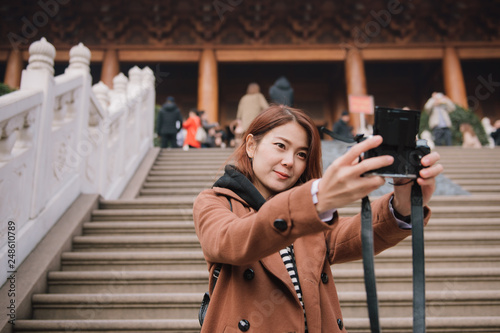 Photography Young asian woman taking a selfie photo with her camera in temple