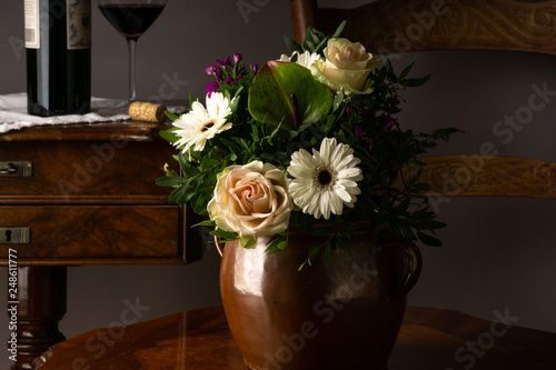 Obraz na płótnie Old vase of ceramic on a chair with flowers and botlle and glass of wine in the background w salonie