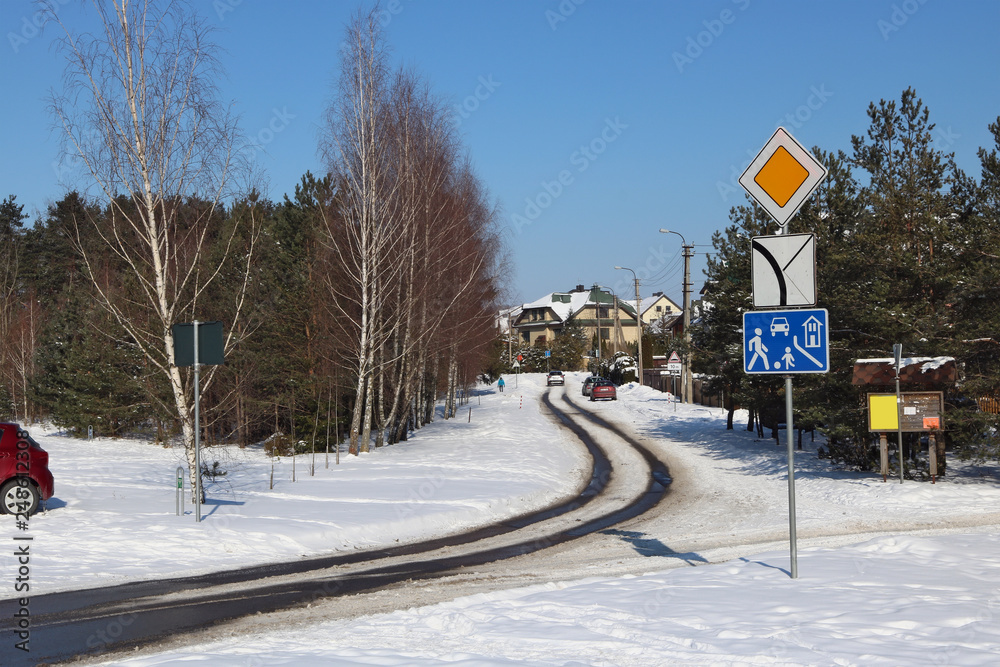 Snow-covered winter  road in a no name village and a lone traveler