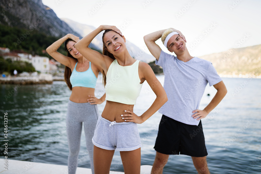 Group of happy people exercising outdoor. Sport, fitness, friendship and healthy lifestyle concept Group of happy people exercising outdoor. Sport, fitness, friendship and healthy lifestyle concept